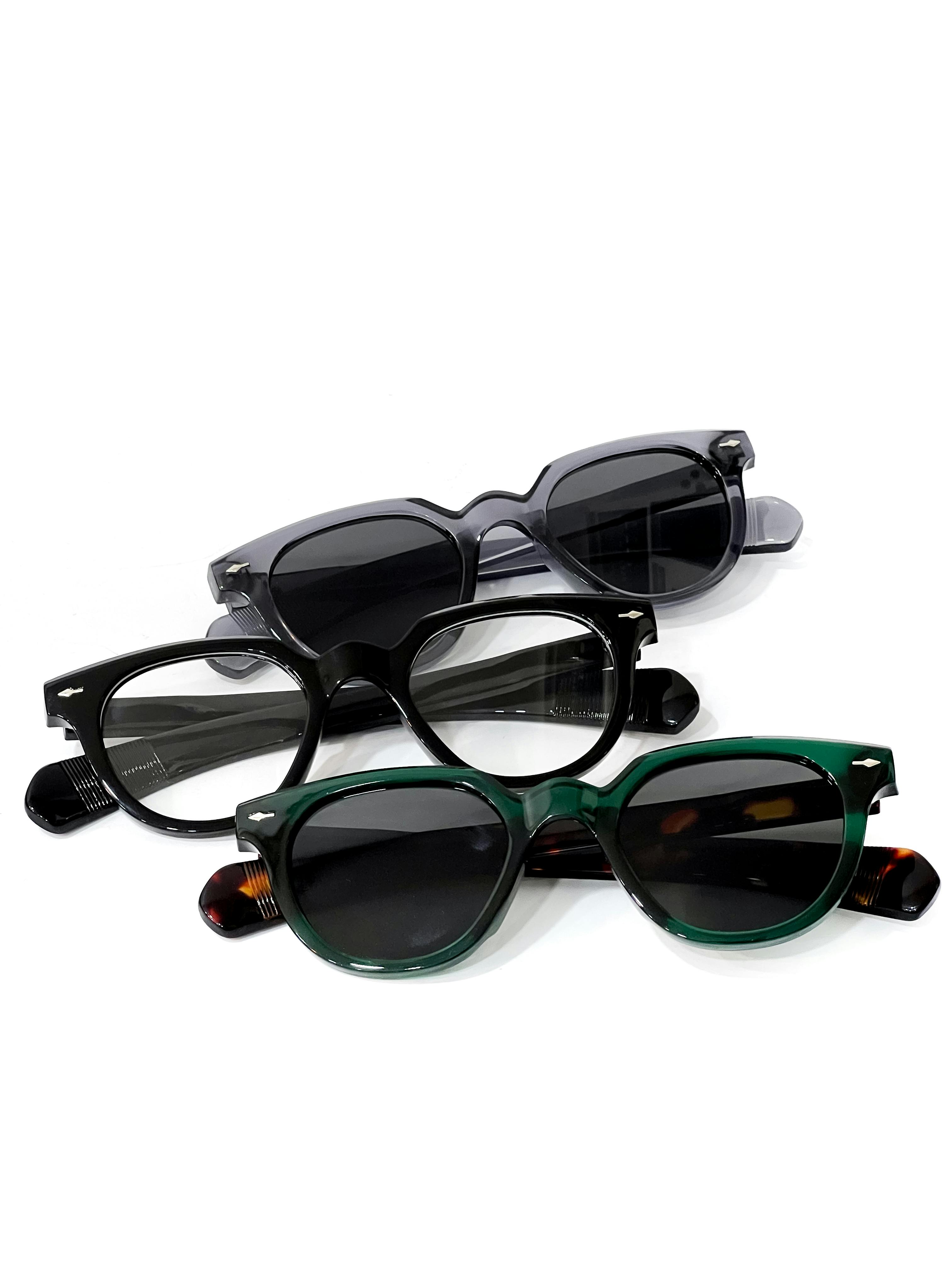Flat lay of five different sunglasses styles arranged on a cream background