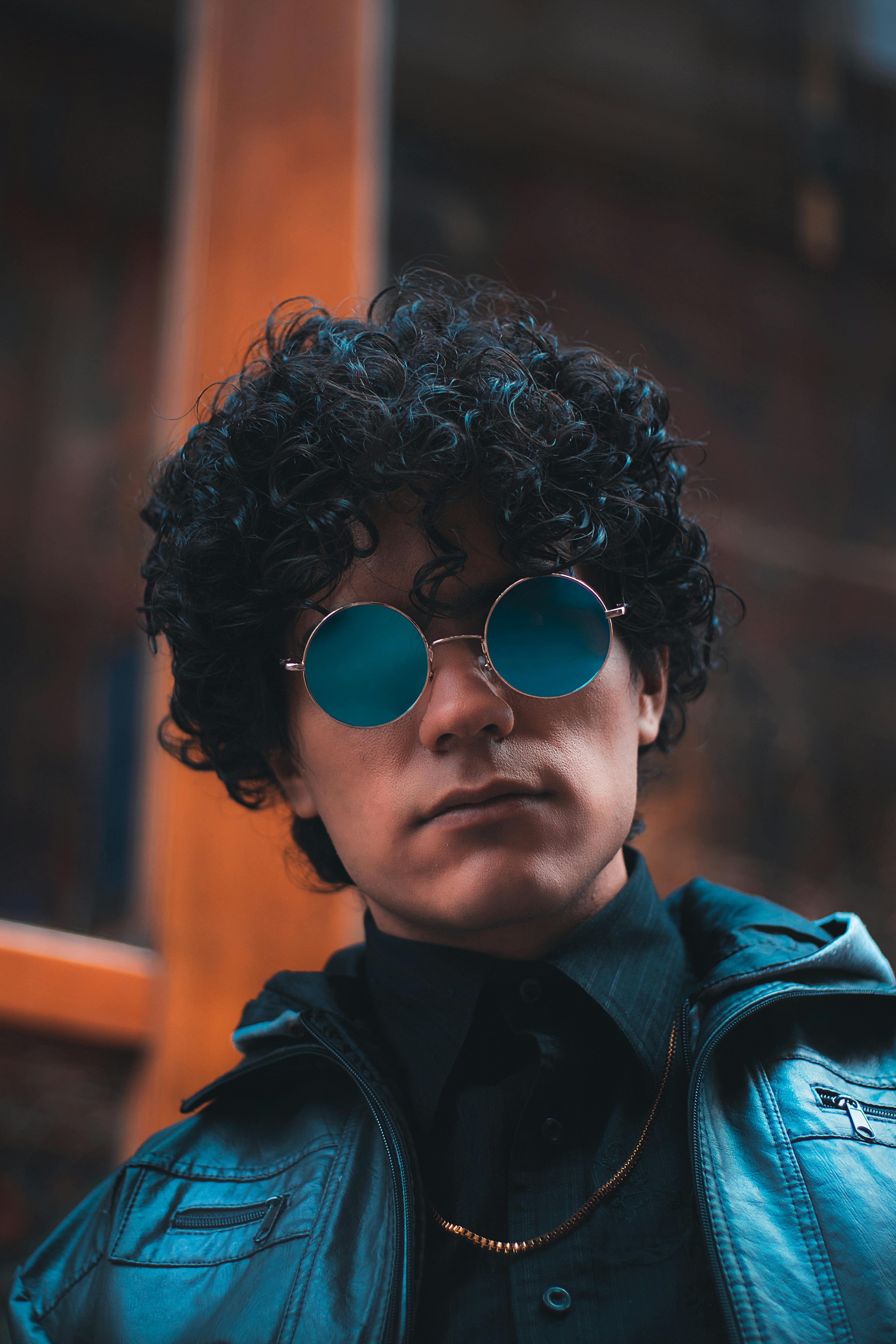 Person with a square jawline wearing round sunglasses